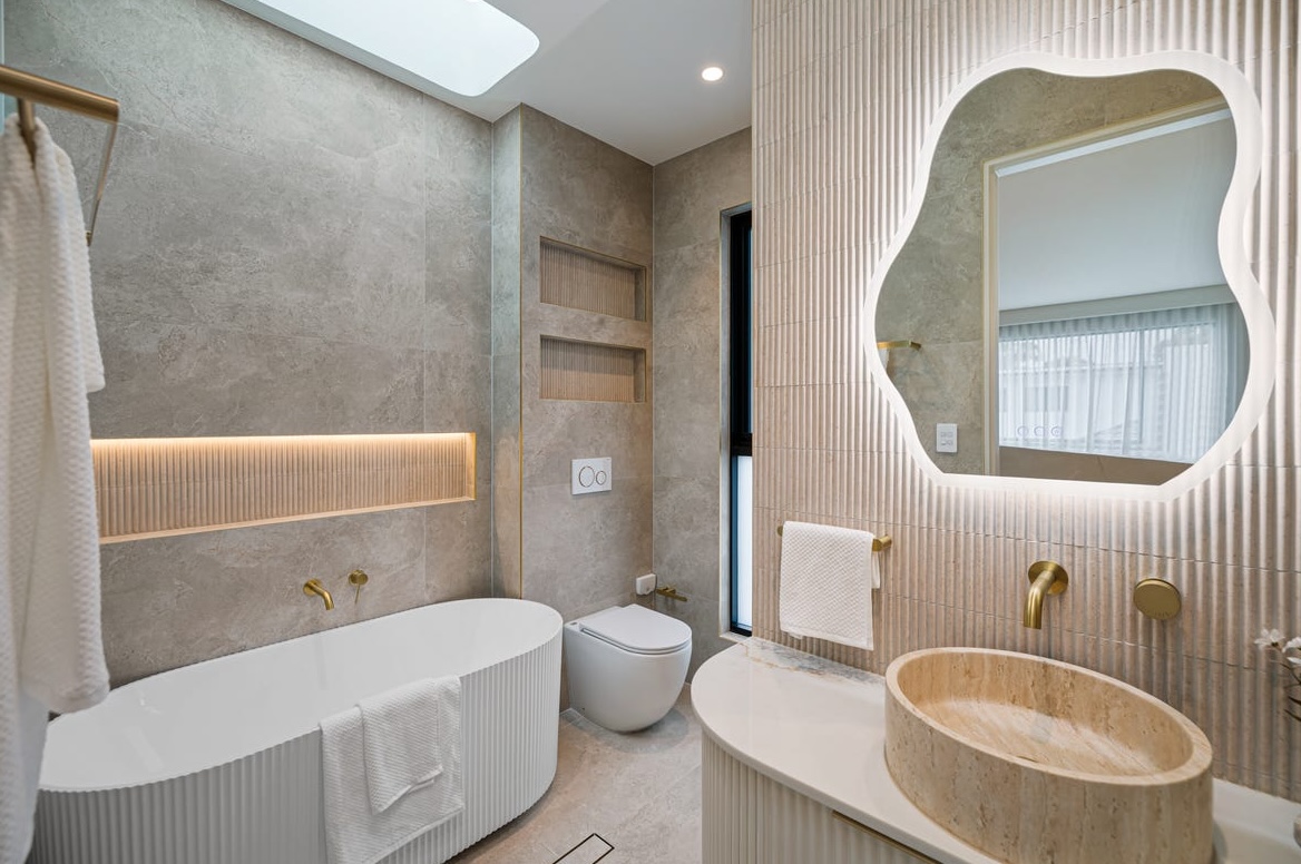 Sculpted mirror above a stone vanity with a backlit niche