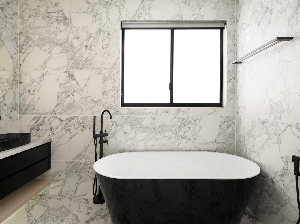 Black freestanding bath against full-height marble